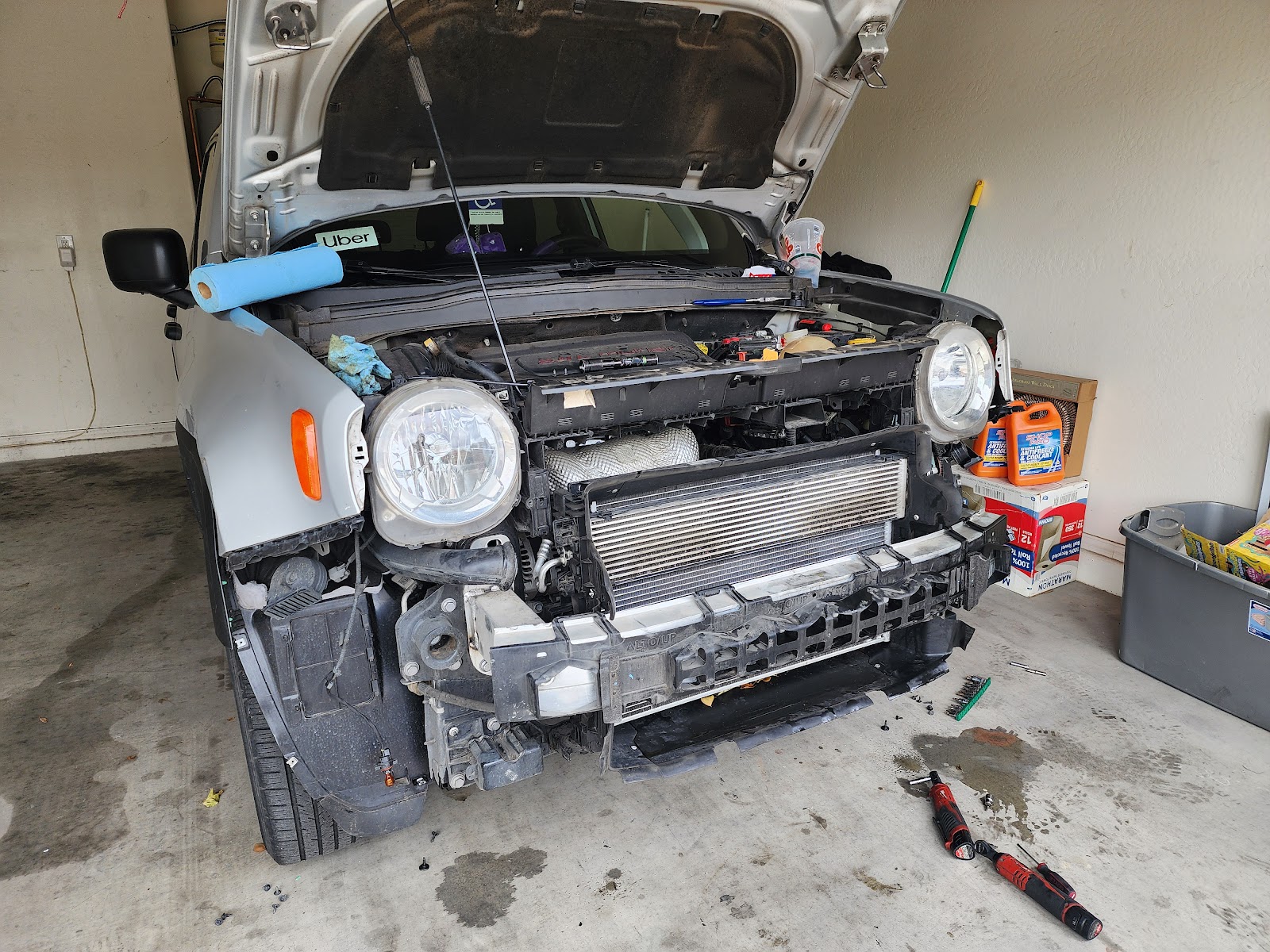 Front bumper off a Jeep Renegade in a customer's garage, intercooler and radiator exposed, tools on the floor