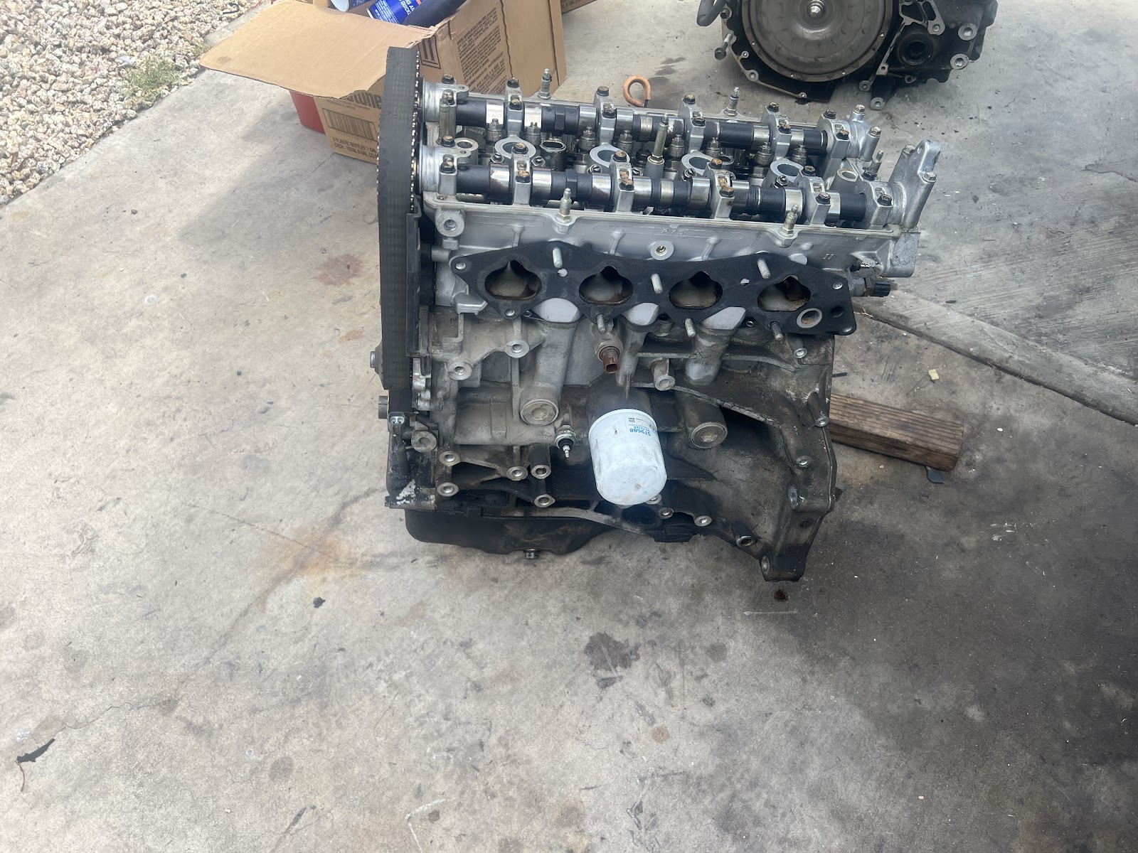 Engine out of the car and sitting on the driveway next to its transmission, mid job